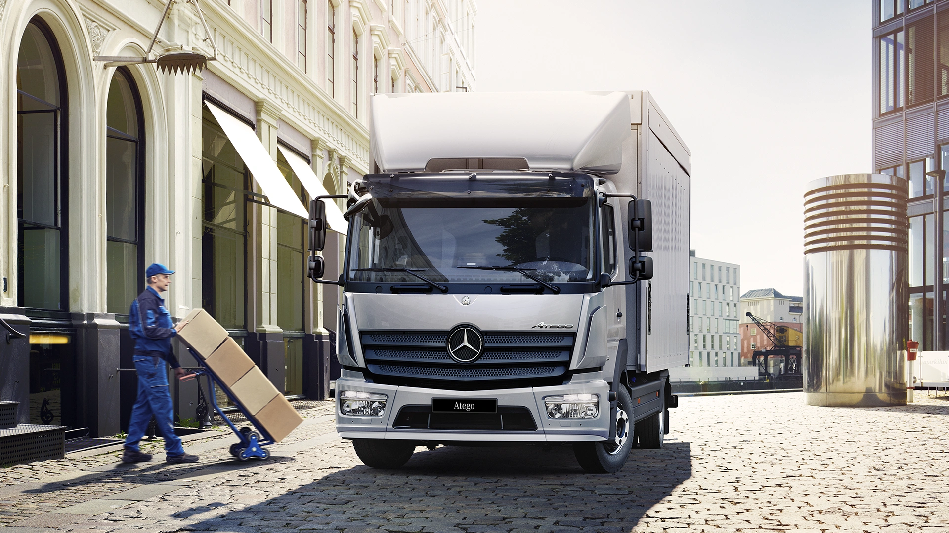 Atego sunkvežimis mieste, šalia darbuotojas važa krovinį