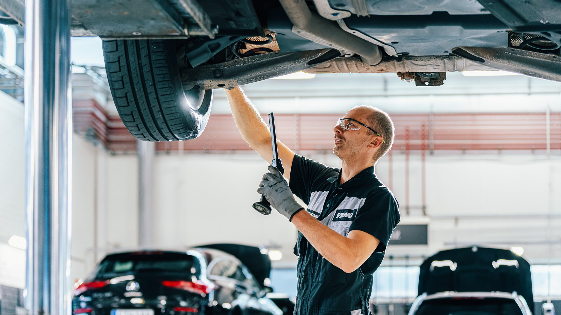 „Mercedes“ mechanikas yra po automobiliu ir tikrina valdymo svirties tarpus.