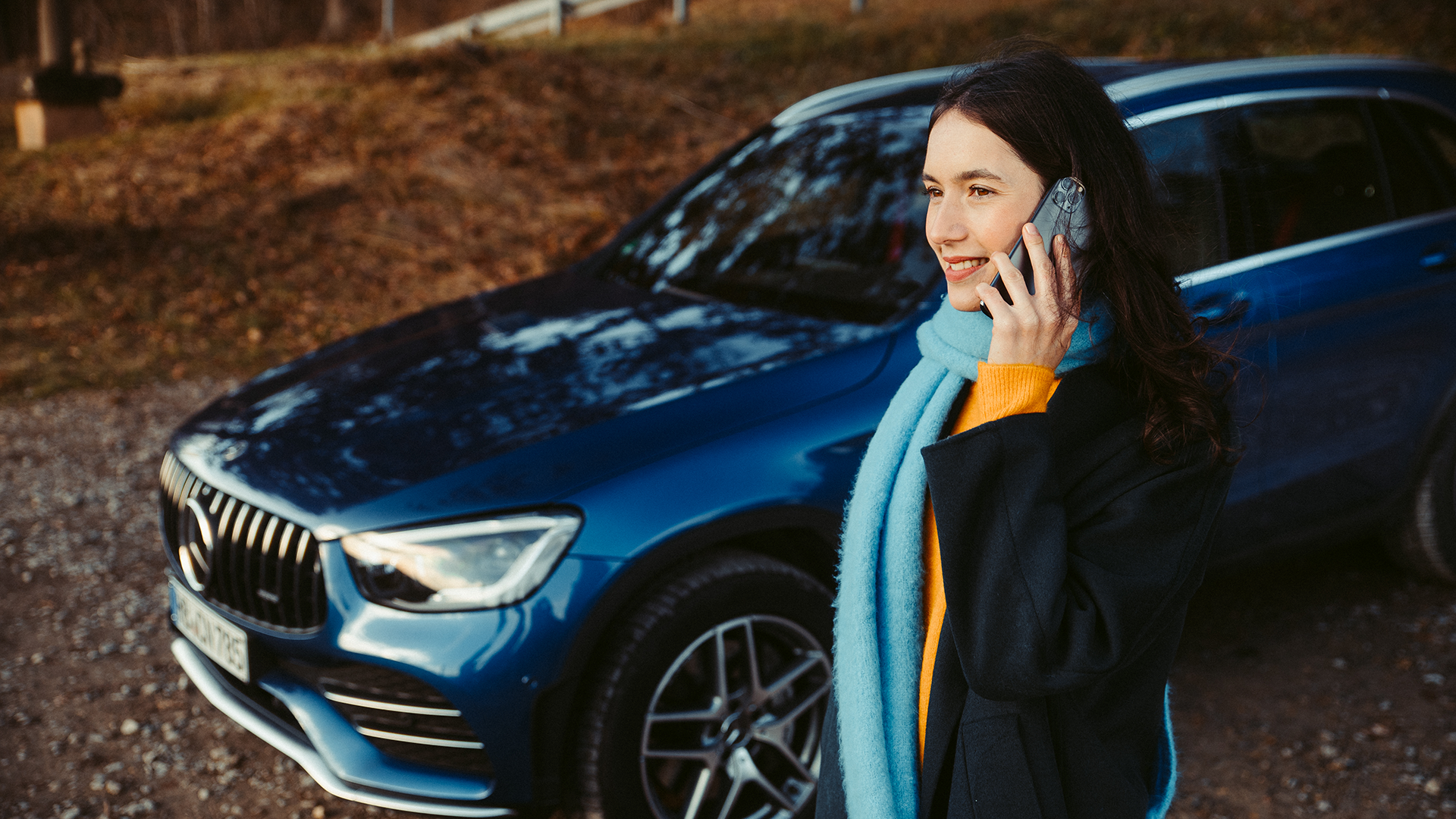 Šalia Mersedes-Benz esanti moteris kalba telefonu.