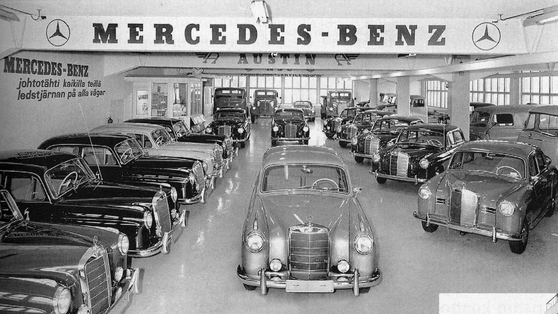 Nespalvota automobilių prekybos centro nuotrauka šeštajame dešimtmetyje. Mercedes-Benz automobiliai iš eilės kairėje ir viduryje vienas automobilis nufotografuotas iš priekio.