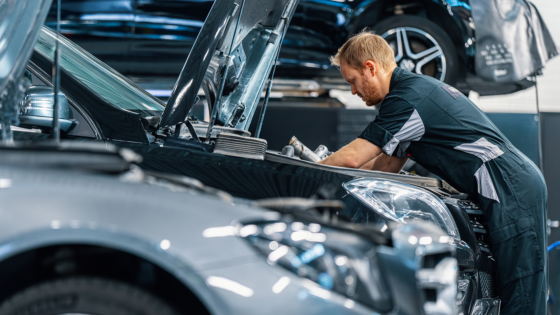 Mercedes mechanikas atlieka automobilio variklio skyriaus techninę priežiūrą.