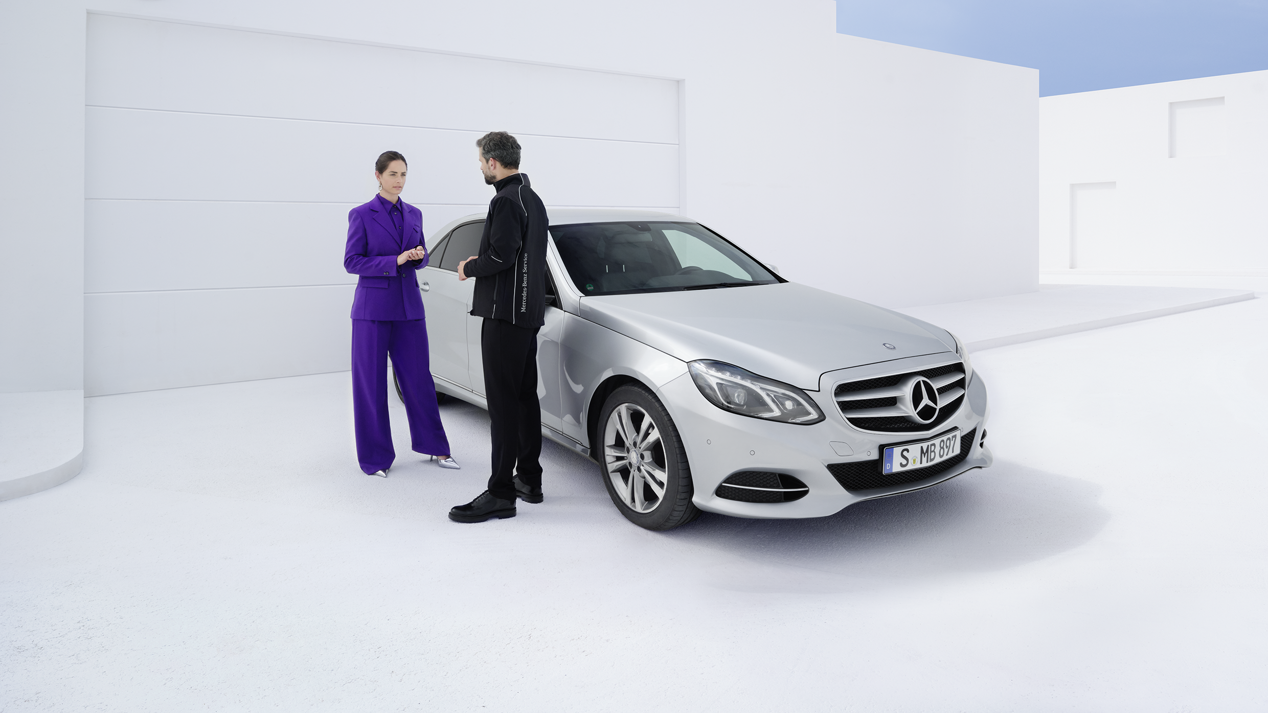 Du žmonės šalia E klasės „Mercedes-Benz“.