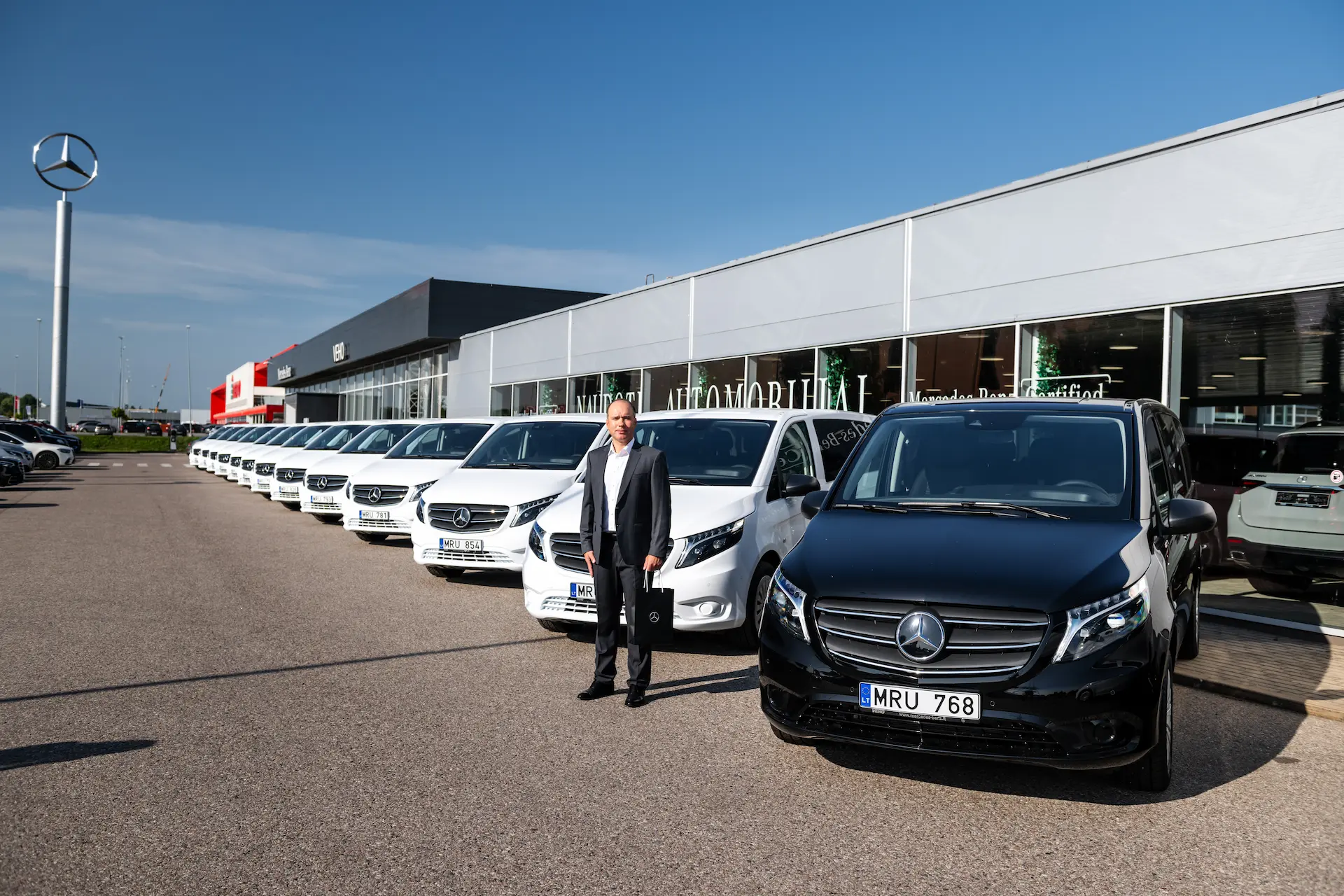 Įmonės atstovas įsigytų Mercedes-Benz Vito fone prie atstovybės