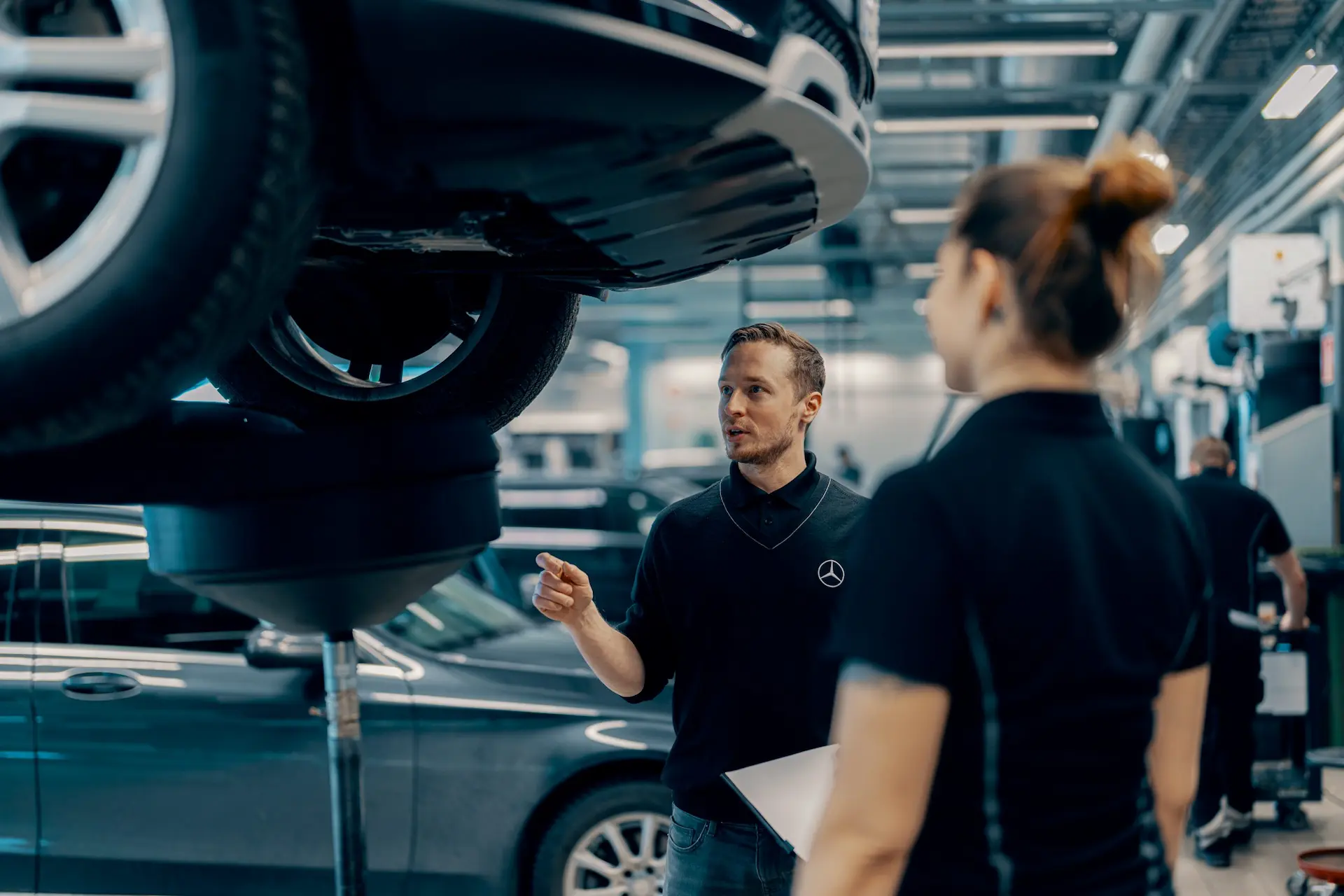 Serviso darbuotojai apžiūri pakeltą automobilį