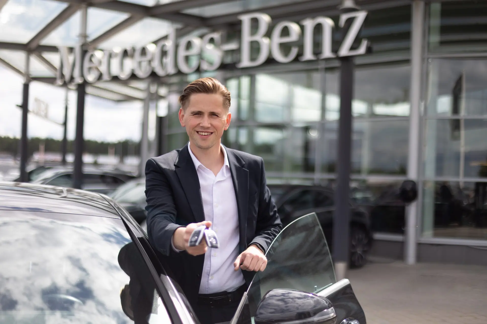 Automobilių pardavėjas prie automobilio, fone Vilniaus salonas